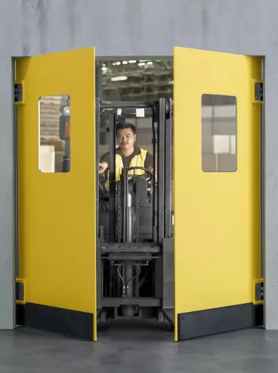 Yellow industrial flip flop doors with a forklift operator